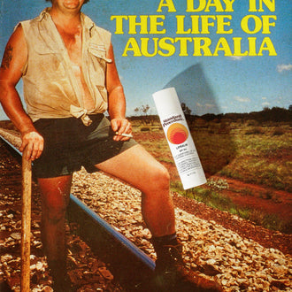 Lip balm vitamin C product shown over a vintage Australian outback scene with a man standing by railroad tracks.