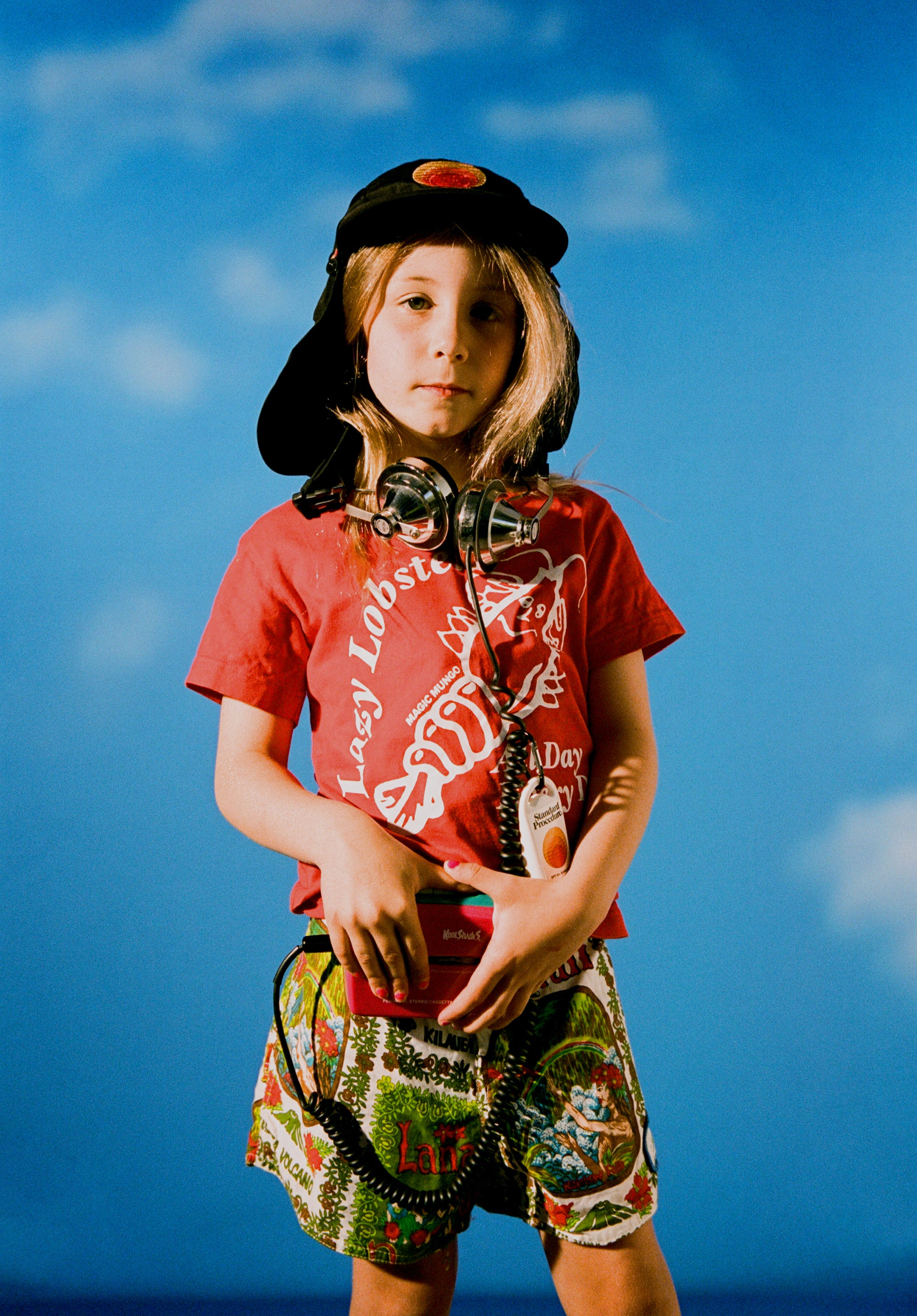 Surf sun hat worn by a child against a blue sky backdrop, featuring a wide brim, protective neck flap, and Standard Procedure logo for ultimate sun protection