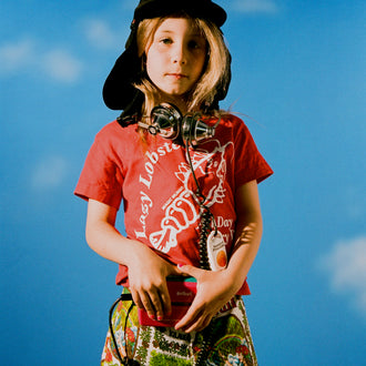 Surf sun hat worn by a child against a blue sky backdrop, featuring a wide brim, protective neck flap, and Standard Procedure logo for ultimate sun protection