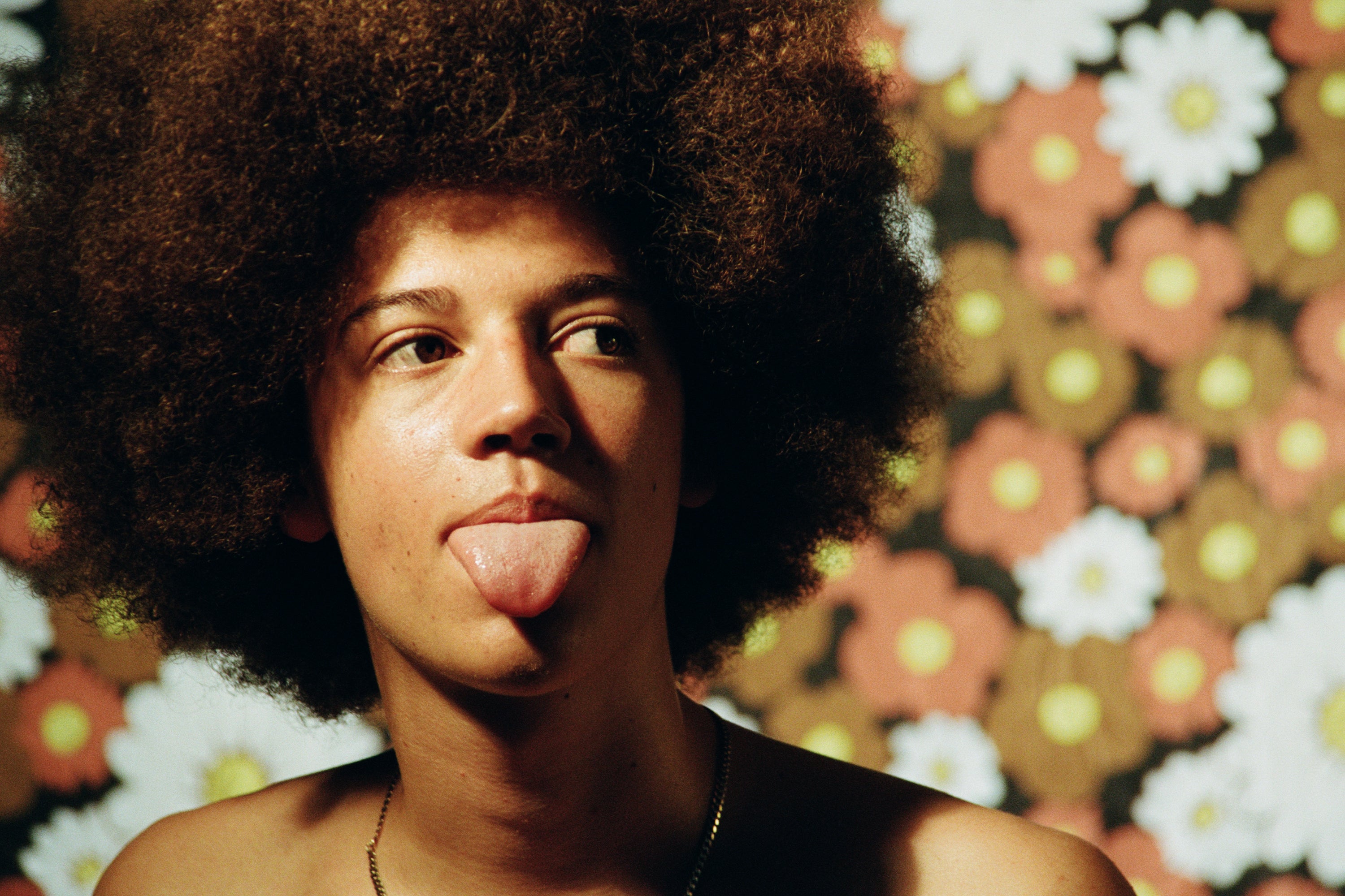 A person with curly hair against a floral background, emphasizing a carefree, sun-kissed look that reflects outdoor surfers sunblock skincare